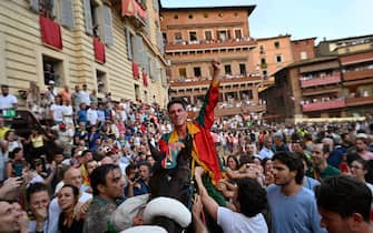 Italian jockey Giovanni Atzeni (C) riding Zio Frac for the Drago district, celebrates after winning the historical Italian horse race "Palio di Siena" on July 2, 2022 in Siena, Tuscany. (Photo by Alberto PIZZOLI / AFP) (Photo by ALBERTO PIZZOLI/AFP via Getty Images)