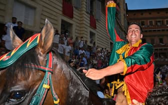 Italian jockey Giovanni Atzeni, riding Zio Frac for the Drago district, celebrates after winning the historical Italian horse race "Palio di Siena" on July 2, 2022 in Siena, Tuscany. (Photo by Alberto PIZZOLI / AFP) (Photo by ALBERTO PIZZOLI/AFP via Getty Images)