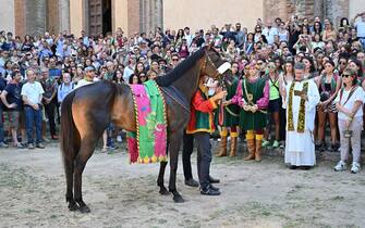 Italian jockey Giovanni Atzeni, a.k.a. Tittia, who is to ride the horse "Zio Frac" for the "Drago" (Dragon) contrada (City Ward), holds his horse during its benediction by a priest (R) at the contrada's church, ahead of the historical Italian horse race "Palio di Siena" on July 2, 2022 in Siena, Tuscany. (Photo by Alberto PIZZOLI / AFP) (Photo by ALBERTO PIZZOLI/AFP via Getty Images)