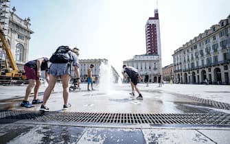 C'è chi trova refrigerio per contrastare l'emergenza caldo facendo il bagno nelle fontane di piazza Castello: i termometri segnano 34 gradi nel pomeriggio del 14 luglio 2022 a Torino, in centro ANSA/JESSICA PASQUALON