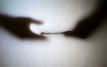 Silhouette of business man hands giving bribe isolated on gray background