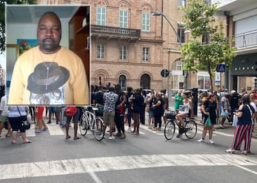 La minifestazione della comunità nigeriana sul luogo dell'omicidio e una foto di Alika Ogorchukwu, l'ambulante nigeriano di 39 anni, aggredito e ucciso ieri pomeriggio in pieno centro a Civitanova Marche, 30 luglio 2022. ANSA