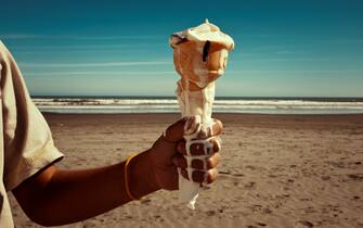 Boy holds melting ice cream cone at beach