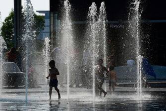 Kids play with water sources at Aulenti square in Milan during a heatwave on June 26, 2019. - Meteorologists blamed a blast of torrid air from the Sahara for the unusually early summer heatwave, which could send thermometers up to 40 degrees Celsius (104 Fahrenheit) in some places on June 27 and 28. Experts say such heatwaves early in the summer are likely to be more frequent as the planet heats up. (Photo by Miguel MEDINA / AFP)        (Photo credit should read MIGUEL MEDINA/AFP via Getty Images)