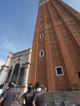 Vigili del Fuoco osservano la parete nord del campanile di San Marco, da dove si son staccati frammenti dei mattoni a causa del nubifragio che oggi, 18 agosto 2022, si è abbattuto sulla città. ANSA/ANDREA MEROLA                               