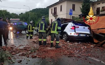 I vigili del fuoco intervengono per rimuovere un tetto volato via da una abitazione che ha  centrato un auto a Fornaci di Barga (Lucca), 18 agosto 2022.
ANSA/VIGILI DEL FUOCOEDITORIAL USE ONLY NO SALES