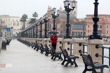 BARI, ITALY - JANUARY 10:  A man shelters from the rain under an umbrella as he walks along an empty seafront on January 10, 2022 in Bari, Italy. A cold disturbance is crossing Italy, causing a lowering of temperatures, snowfalls up to hilly altitudes on part of the South. (Photo by Donato Fasano/Getty Images)