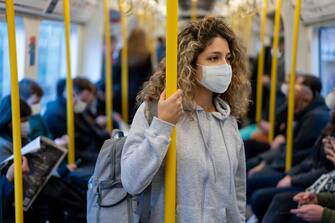 Beautiful young woman riding on the metro wearing a facemask to avoid an infectious disease - COVID-19 lifestyle concepts