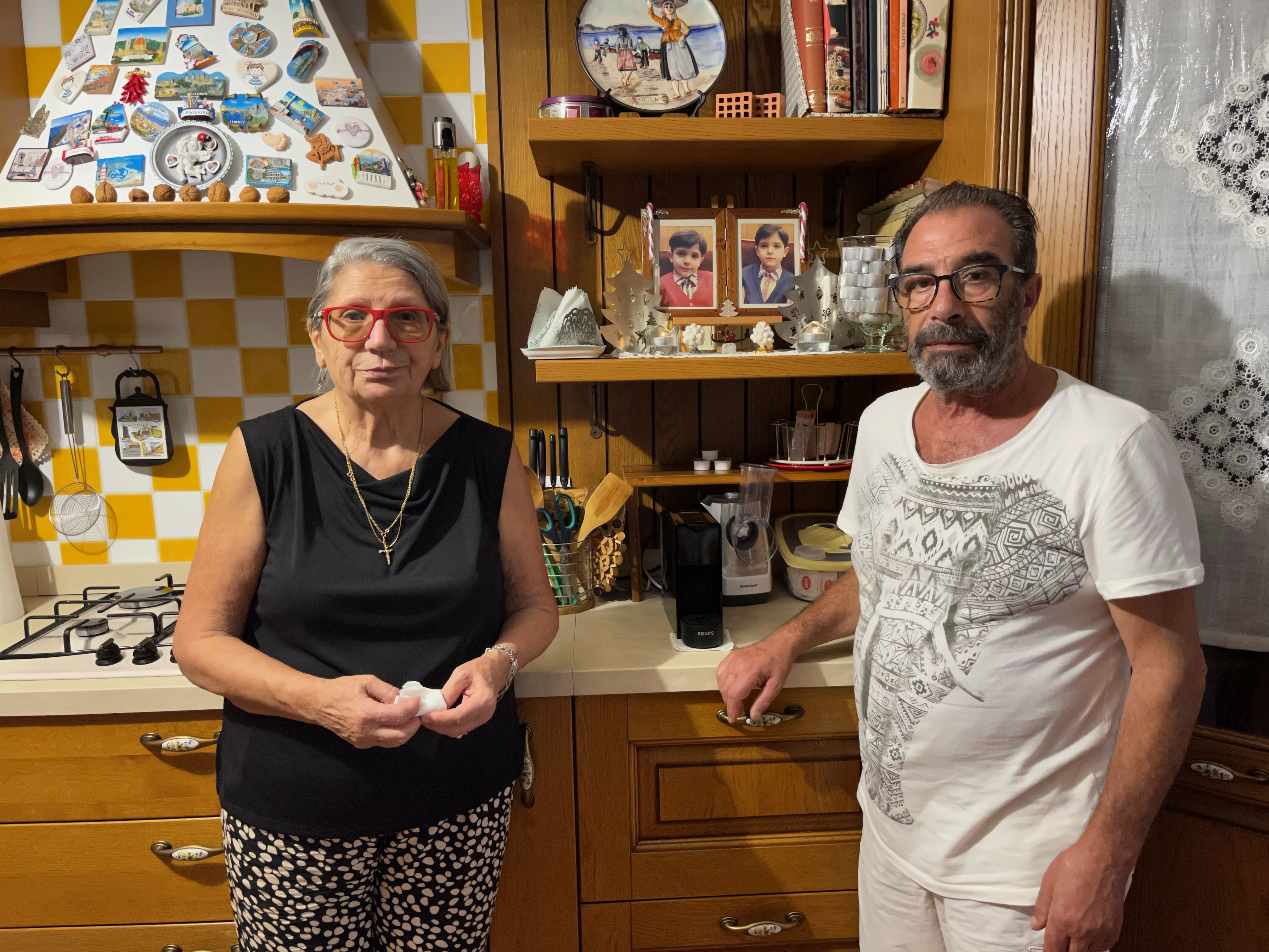 Maria e Ciro Riggio posano nella loro casa, con le foto dei gemelline alle spalle