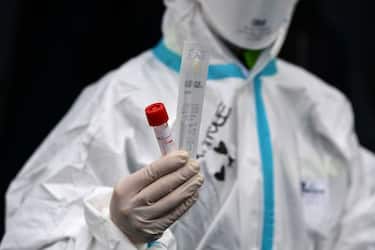 A hospital employee wearing protection mask and gear shows a swab, a cotton wab for taking mouth specimen, used at a temporary emergency structure set up outside the accident and emergency department, where any new arrivals presenting suspect new coronavirus symptoms will be tested, at the Brescia hospital, Lombardy, on March 13, 2020. (Photo by Miguel MEDINA / AFP) (Photo by MIGUEL MEDINA/AFP via Getty Images)
