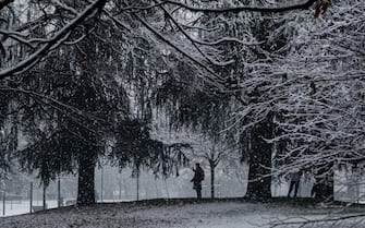 MILAN, ITALY - DECEMBER 8: A man takes a picture under the trees in Parco Sempione as snow falls in Milan, Italy on 08/12/21 (Photo by Piero Cruciatti/Anadolu Agency via Getty Images)
