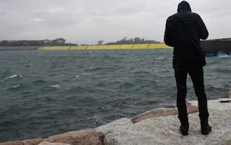 A man stands on dam near the mobile gates of the MOSE Experimental Electromechanical Module (Rear in yellow) that protects the city of Venice from floods, at the Malamocco inlet off Venice's Lido on October 3, 2020 during a high tide "Alta Acqua" phenomenon, following a peak of water following bad weather and potential intense sirocco winds along the entire Adriatic basin. - Together with other measures, such as coastal reinforcement, the raising of quaysides, and the paving and improvement of the lagoon, MOSE is designed to protect Venice and the lagoon from tides of up to 3 metres. (Photo by ANDREA PATTARO / AFP) (Photo by ANDREA PATTARO/AFP via Getty Images)