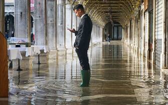 A waiter stands in floodwater at a cafe as the waits for the tide to recede in St. Marks Square in Venice, Italy, on Saturday, Nov. 26, 2022. The frequency of flooding, known as acqua alta, has been increasing steadily in Venice in recent years. Photographer: Andrea Merola/Bloomberg via Getty Images