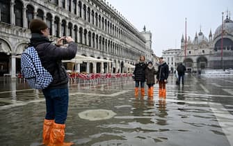 A man takes photos on a flooded St. Mark's square in Venice on December 10, 2022, following an "Alta Acqua" high tide event, too low to operate the MOSE Experimental Electromechanical Module that protects the city of Venice from floods. (Photo by ANDREA PATTARO / AFP) (Photo by ANDREA PATTARO/AFP via Getty Images)
