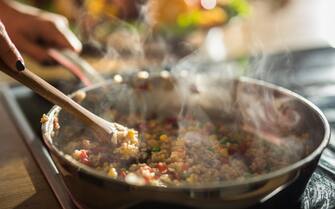 Close up of unrecognizable woman preparing healthy meal in frying pan.