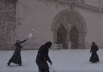 Frati francescani giovano a palle di neve fuori dalla Basilica di San Francesco