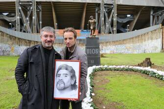 NAPLES, ITALY - 2021/11/25: The sculptor Domenico Sepe (on left) with a man holds a picture of Maradona, in front of his statue of Diego Armando Maradona,  in front of the Diego Armando Maradona stadium. (Photo by Marco Cantile/LightRocket via Getty Images)