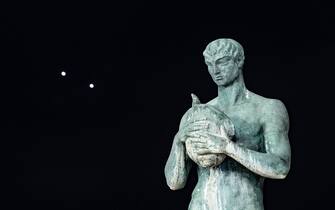 Planets Jupiter and Venus in conjunction are seen after sunset behind a statue in LAquila, Italy, on march 1st, 2023. Planets seem to be very close (less than a degree away from each other). Moons (satellites) of Jupiter are visible even with a telephoto lens. (Photo by Lorenzo Di Cola/NurPhoto via Getty Images)