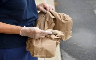 1271779982 Muhlenberg twp., PA - September 10: A school district employee holds bags containing breakfasts and a lunchs, to distribute. At the Muhlenberg Elementary Center in Muhlenberg twp, PA Thursday morning September 10, 2020 where school district employees were distributing grab and go meals to students. The program has been going on since the start of the COVID-19 pandemic and is continuing this school year as all education in the district is being done virtually. (Photo by Ben Hasty/MediaNews Group/Reading Eagle via Getty Images)