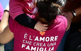 A woman wearing a jersey reading "It is love that creates a family" holds a baby during a demonstration by gay rights and civil society groups in Milan on March 18, 2023, against moves by Italy's right-wing government to restrict the rights of same-sex parents. (Photo by GABRIEL BOUYS / AFP) (Photo by GABRIEL BOUYS/AFP via Getty Images)