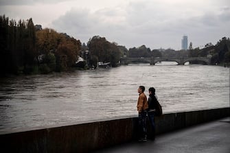 People look at the river Po in the city center of Turin on November 6, 2018 after its level rose overnight following heavy rain. - Heavy rains continued to lash northern Italy on November 6, with swollen rivers and Lake Maggiore, the country's second largest lake, close to overflowing. (Photo by MARCO BERTORELLO / AFP)        (Photo credit should read MARCO BERTORELLO/AFP via Getty Images)