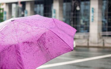 Bad weather. Rainy day. Umbrella with raindrops on the city background. City street style.