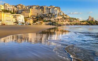 Sperlonga, Italy -- A sunset view of the city of Sperlonga, in the south of Rome, perched on a rocky outcrop facing the Tyrrhenian Sea. Sperlonga was founded by the Romans and became the site of numerous imperial villas, including the famous villa of Emperor Tiberius, whose archaeological remains are still preserved today. Sperlonga is a very popular place in summer for its beautiful and peaceful beaches.