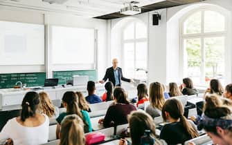 A university professor addressing his pupils during a lecture in a bright, modern lecture theatre.