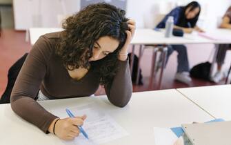 A high school student is having a hard time while focusing on a test during class.