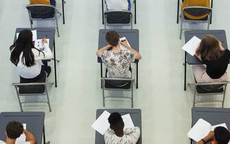 Overhead view high school students taking exam at desks in rows in school classroom