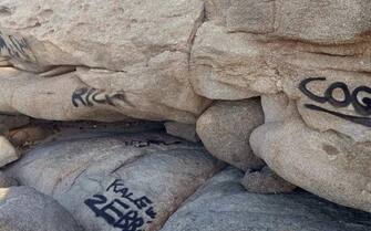 Una scritta nera, forse una
firma con la bomboletta spray, su una roccia di granito davanti
al mare azzurro di Villasimius, lungo la costa sud orientale
della Sardegna, 25 Agosto 2023. ANSA/US GUARDIE AMBIENTALI SARDEGNA