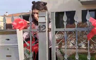 Un fermo immagine tratto da un video mostra Elena Cecchettin mettere fiocchi rossi sul cancello per festeggiare la laurea che la sorella Giulia avrebbe dovuto discutere oggi, 16 novembre 2023.