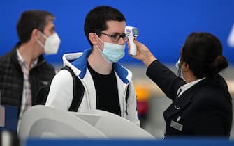 Passengers wearing face masks or covering due to the COVID-19 pandemic, have their temperature taken as they queue at a British Airways check-in desk at Heathrow airport, west London, on July 10, 2020. - The British government on Friday revealed the first exemptions from its coronavirus quarantine, with arrivals from Germany, France, Spain and Italy no longer required to self-isolate from July 10. Since June 8, it has required all overseas arrivals -- including UK residents -- to self-quarantine to avoid the risk of importing new cases from abroad. (Photo by DANIEL LEAL-OLIVAS / AFP) (Photo by DANIEL LEAL-OLIVAS/AFP via Getty Images)
