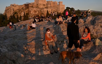 People enjoy a sunset in the Aeropagus hill overlooking the Ancient Acropolis in Athens on May 5, 2020 as Greece gradually eases its lockdown against the spread of the COVID-19, the novel coronavirus, lifting up most of the restrictions on citizens' movement. (Photo by Louisa GOULIAMAKI / AFP) (Photo by LOUISA GOULIAMAKI/AFP via Getty Images)