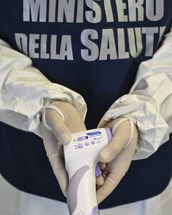 CATANIA, ITALY - MARCH 12: A thermometer being used to measure the body temperature of passengers arriving at Catania airport on March 12, 2020 in Catania, Italy.  The Italian government has escalated the Coronavirus Lockdown measures by ordering the closure of all commercial activities except supermarkets, pharmacies and banks, with factories and transportation to also remain up and running.  (Photo by Fabrizio Villa/Getty Images)