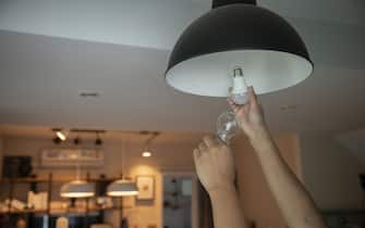 man changing compact-fluorescent (CFL) bulbs with new LED light bulb.