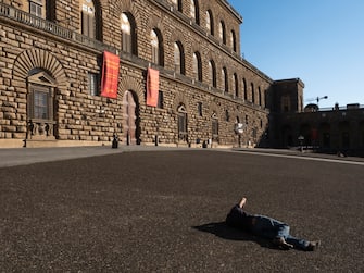 Florence, Italy May 21st 2020.  A man lies on the floor of Piazza Pitti. Before Coronavirus struck Italy ,in March 2020, the square was usually full of tourists, taking relax or in line for get inside Palazzo Pitti Museum.  Due to the spread of the epidemic, the city of Florence is facing deep economic issues because of the lack of tourists. Tourism represent a big part of the incomes of the city.