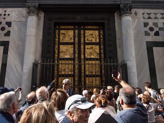 Florence, Italy October 27th 2018. Tourists looking to Ghiberti's door in Piazza Duomo. The door is the main entrance of Battistero di St. Giovanni located in Piazza del Duomo in front of the Cathedral of Santa Maria del Fiore.