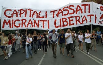 GEN14-20010719-GENOA, ITALY: Demonstrators carry a placard reading "Capitali tassati, Migranti liberati" (Put taxes on the capital, free the immigrants) as about 25 000 people protest in the center of Genua against the G8 (Group of Eight) summit, Thursday 19 July 2001, a day before the start of the conference. Heads of state and government of the G8 countries will meet here 20 to 22 July amid heightened security to deal with an expected 120,000 anti-globalisation demonstrators. EPA PHOTO EPA/ANJA NIEDRINGHAUS/hh

