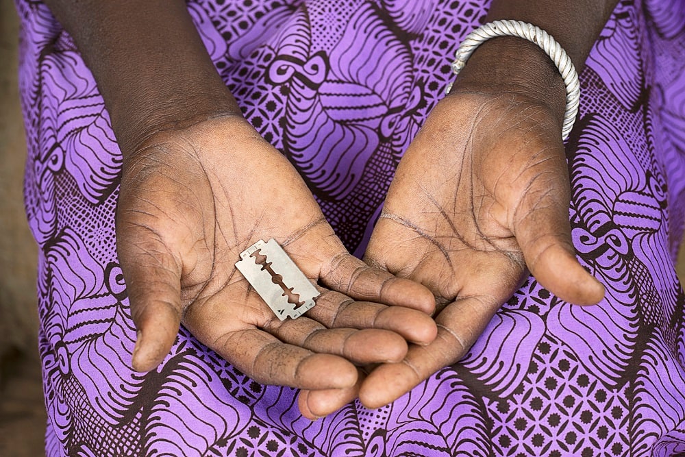 A woman holds a razor blade in Burkina Faso.