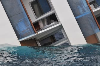 GIGLIO PORTO, ITALY - JANUARY 16: The cruise ship Costa Concordia lies stricken off the shore of the island of Giglio, on January 16, 2012 in Giglio Porto, Italy. More than four thousand people were on board when the ship hit rocks last Friday. The official death toll is now six, with a further 16 people still missing. The rescue operation was temporarily suspended earlier due to the ship moving as it slowly sinks further into the sea. (Photo by Laura Lezza/Getty Images)