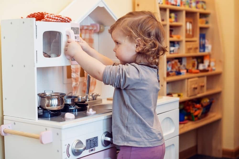 toddler girl playing toy kitchen