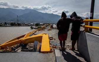 PALU, INDONESIA - OCTOBER 05: Two man looking at a collapsed bridge which was hit by an earthquake and tsunami on October 5, 2018 in Palu, Central Sulawesi, Indonesia. The death toll from last weeks earthquake and tsunami has risen to at least 1,558 but widely expected to rise as officials said on Friday the number of victims of the liquefaction could be up to a thousand. Power had returned to parts of the city and fuel shipments have begun to flow back but some affected towns remain inaccessible with the infrastructure badly damaged. A tsunami triggered by a magnitude 7.5 earthquake slammed into Indonesia's coastline on the island of Sulawesi which destroyed or damaged over 70,000 homes as tensions remain high with desperate survivors trying to secure basics like clean water and fuel for generators. (Photo by Ulet Ifansasti/Getty Images)