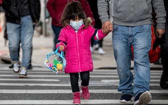 A girl, wearing a mask, walks down a street in the Corona neighborhood of Queens on April 14, 2020 in New York City. - New York will start making tens of thousands of coronavirus test kits a week, its mayor announced Tuesday, as the city looks to boost testing capacity with a view to ending its shutdown. (Photo by Johannes EISELE / AFP) (Photo by JOHANNES EISELE/AFP via Getty Images)