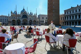 Customers enjoy a drink and the sunshine at the terrace of Cafe Quadri on St. Mark's Square by the basilica in Venice on June 12, 2020 as the country eases its lockdown aimed at curbing the spread of the COVID-19 infection, caused by the novel coronavirus. (Photo by ANDREA PATTARO / AFP) (Photo by ANDREA PATTARO/AFP via Getty Images)