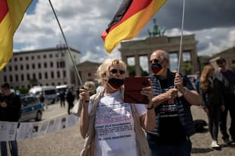 BERLIN, GERMANY - JUNE 06: Participants wearing a protective mask with a German flag colors protest at a rally under the motto "Wake up Germany", which is directed against the government and the measures to contain the coronavirus, at Brandenburger Gate on June 06, 2020 in Berlin, Germany. (Photo by Maja Hitij/Getty Images)