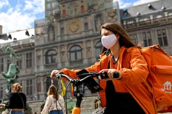 Illustration picture shows a woman working for Take Away, rides a bike with a mask in the city center of Antwerp, Monday 27 July 2020. The Covid-19 contamination numbers are rising again in Belgium. The National Security Council has announced more strict coronavirus measures as from tomorrow, in an attempt to try and keep the contamonation level low.
BELGA PHOTO DIRK WAEM (Photo by DIRK WAEM/BELGA MAG/AFP via Getty Images)