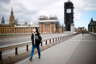 A woman wearing a face mask as a precautionary measure against COVID-19, walks across Westminster Bridge in London on April 2, 2020, as life in Britain continues during the nationwide lockdown to combat the novel coronavirus COVID-19 pandemic. - Prime Minister Boris Johnson said Britain would "massively increase testing" amid a growing wave of criticism on Thursday about his government's failure to provide widespread coronavirus screening. (Photo by Tolga Akmen / AFP) (Photo by TOLGA AKMEN/AFP via Getty Images)
