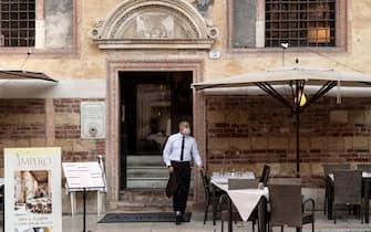 A waiter wearing a protective face mask stands outside a restaurant in Piazza dei Signori on July 25, 2020 in Verona, northern Italy. (Photo by MARCO BERTORELLO / AFP) (Photo by MARCO BERTORELLO/AFP via Getty Images)
