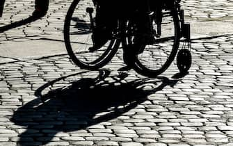 A wheelchair-bound person casts a shadow as it is silhouetted during a 'Disability Pride Parade' by Italian disability organisations, on July 14, 2019 in central Rome. - July is designated as "Disability Pride Month" in honor of the 29th anniversary of the Americans with Disabilities Act that aims to guarantee equal opportunities and rights for people with disabilities. (Photo by Andreas SOLARO / AFP)        (Photo credit should read ANDREAS SOLARO/AFP via Getty Images)